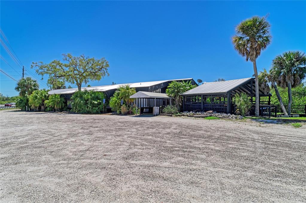 A low-slung commercial building with a gravel parking lot and palm trees under a blue sky — 5611 US HIGHWAY 19, PALMETTO, FL