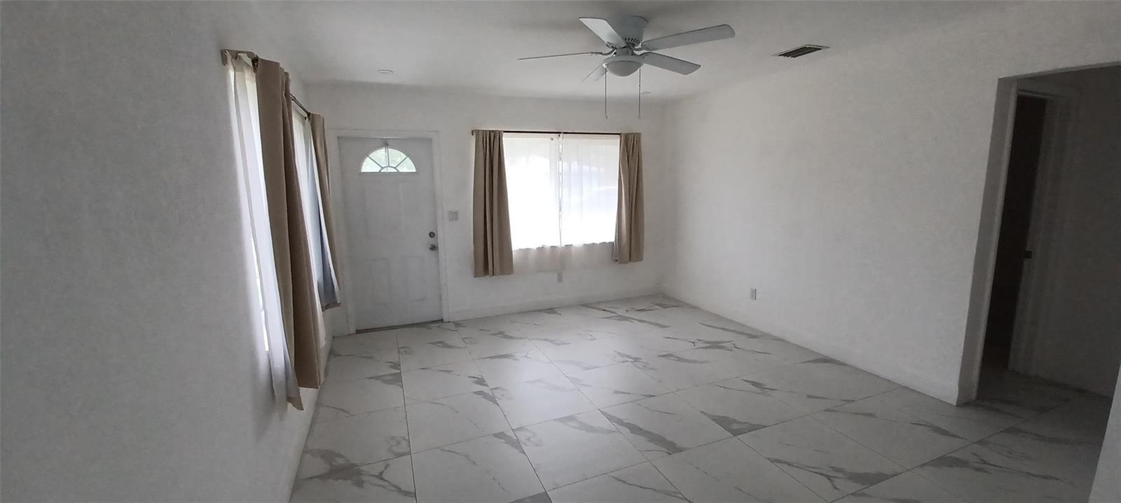 A living room features white walls, a ceiling fan, and light-colored marble-patterned tile flooring — 602 SE 2nd Avenue, Dania Beach FL 33004, DANIA BEACH, FL