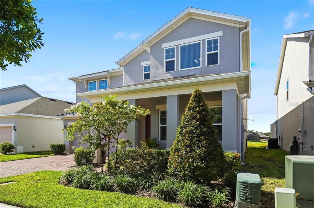 A two-story gray house with a covered front porch and a landscaped front yard — 5026 DOWN COURT, ST CLOUD, FL
