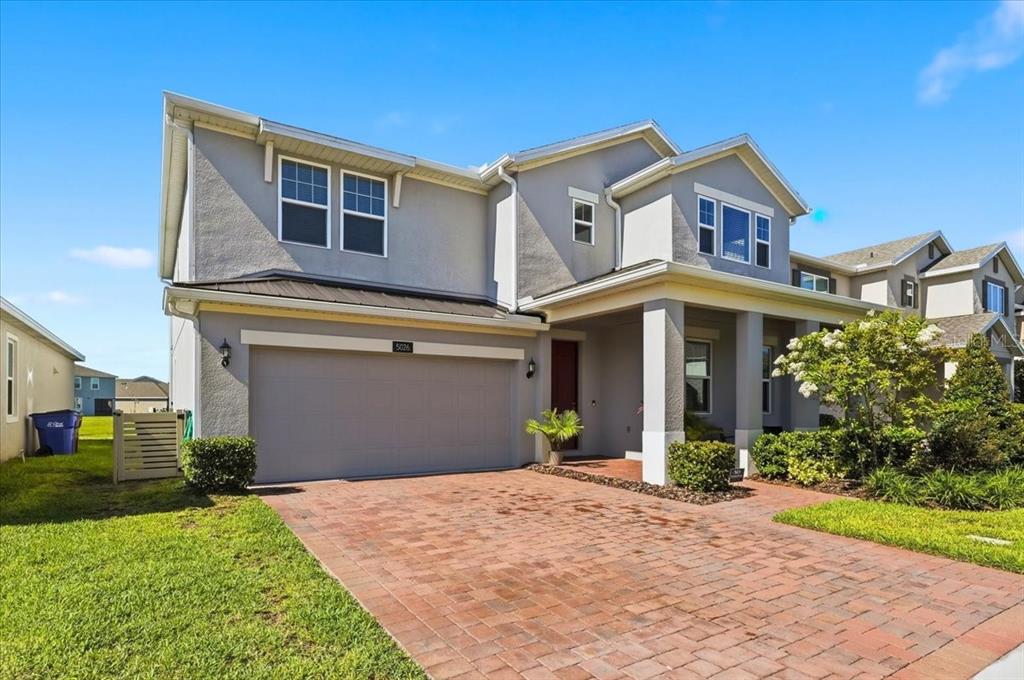 A two-story house with a gray stucco exterior, a brick driveway, and a two-car garage — 5026 DOWN COURT, ST CLOUD, FL