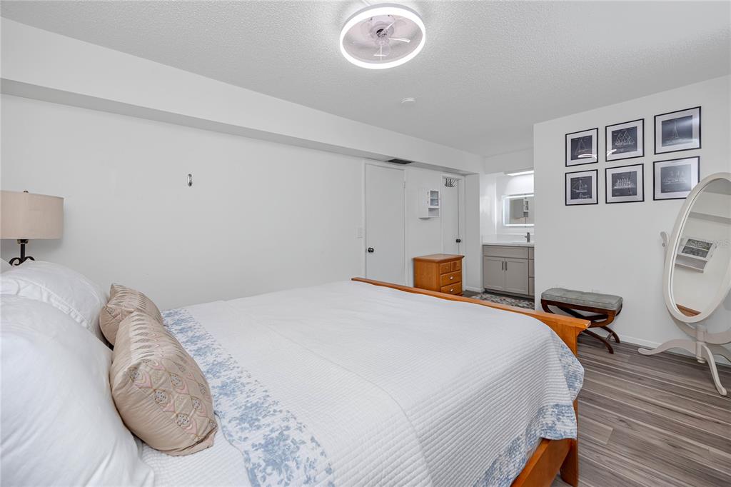 A bedroom features a wooden bed frame, wood-look flooring, and an attached vanity area — 2207 BELLEAIR ROAD UNIT B30, CLEARWATER, FL