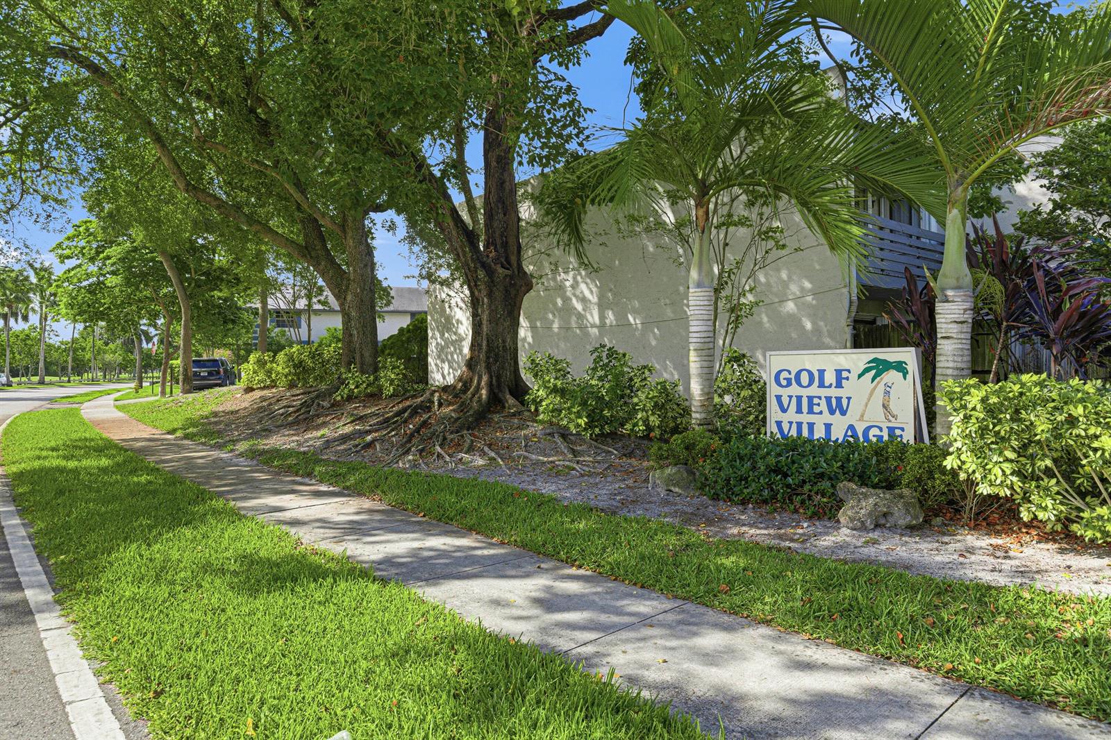 A sidewalk leads past a large tree and a Golf View Village sign — 8207 Fairway Road # 8207, Sunrise FL 33351, SUNRISE, FL