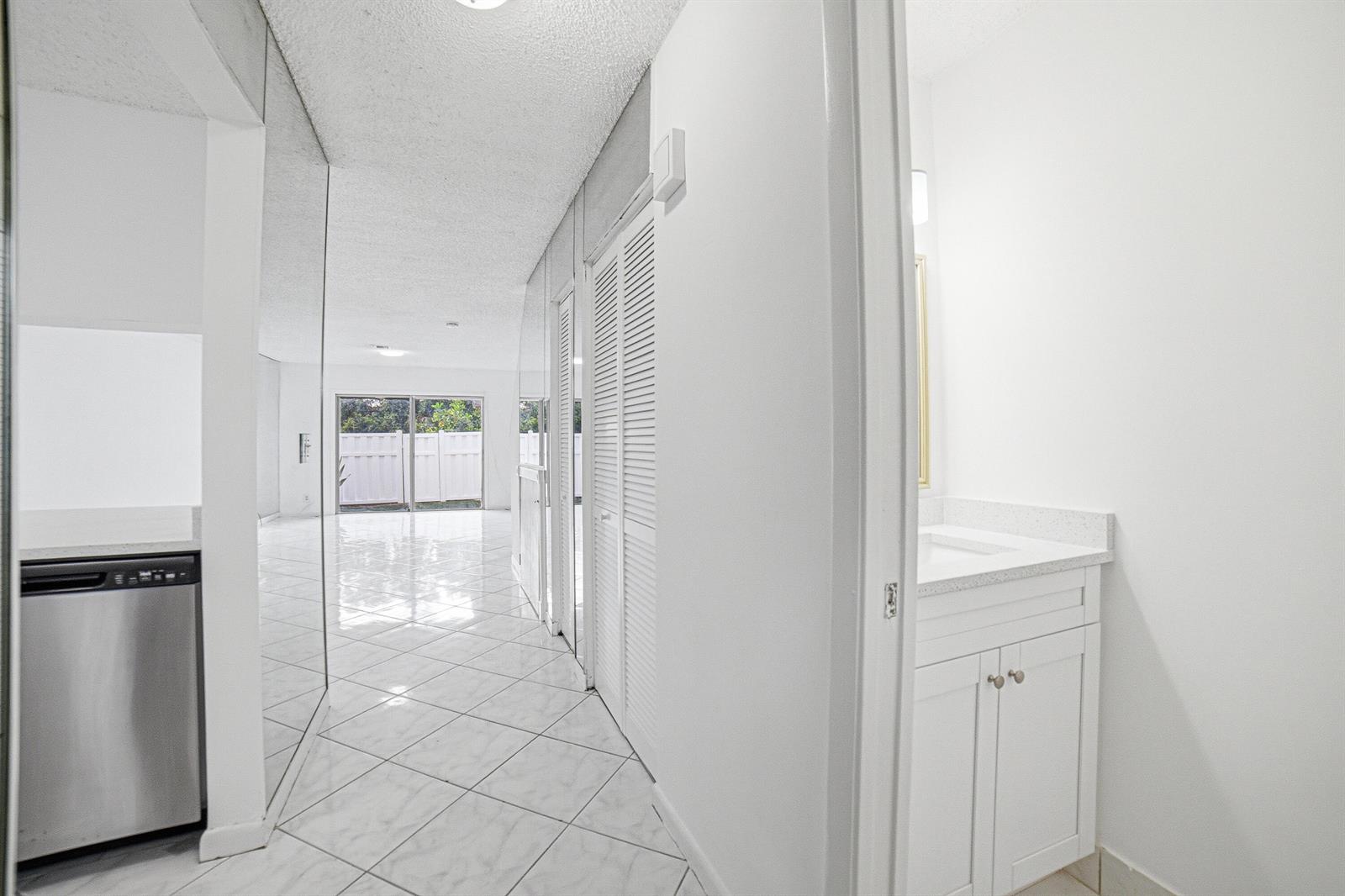 A hallway with white tile floors leads to a living area with sliding glass doors — 8207 Fairway Road # 8207, Sunrise FL 33351, SUNRISE, FL