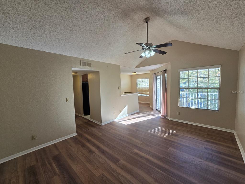 An empty living room features vaulted ceilings, a ceiling fan, and wood-look flooring — 11582 WESTWOOD BOULEVARD UNIT 1436, ORLANDO, FL