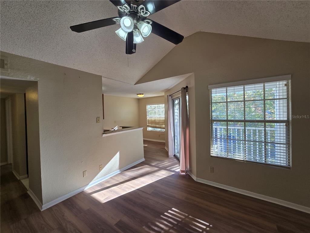 A living room with wood-look flooring, a vaulted ceiling, a ceiling fan, and large windows — 11582 WESTWOOD BOULEVARD UNIT 1436, ORLANDO, FL