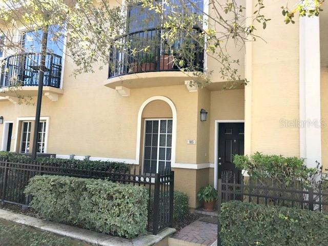 A two-story tan townhouse features a black metal balcony, arched window, and front door — 105 S SHERRILL STREET, TAMPA, FL