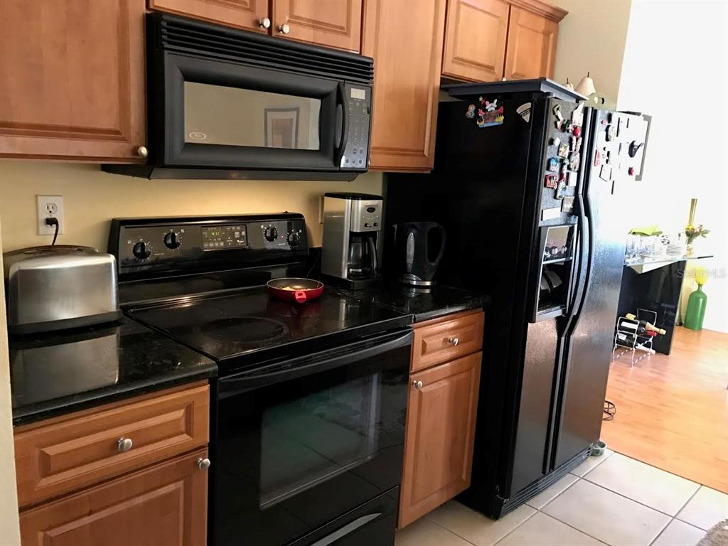 A kitchen featuring wooden cabinets, black appliances, and a black countertop — 105 S SHERRILL STREET, TAMPA, FL