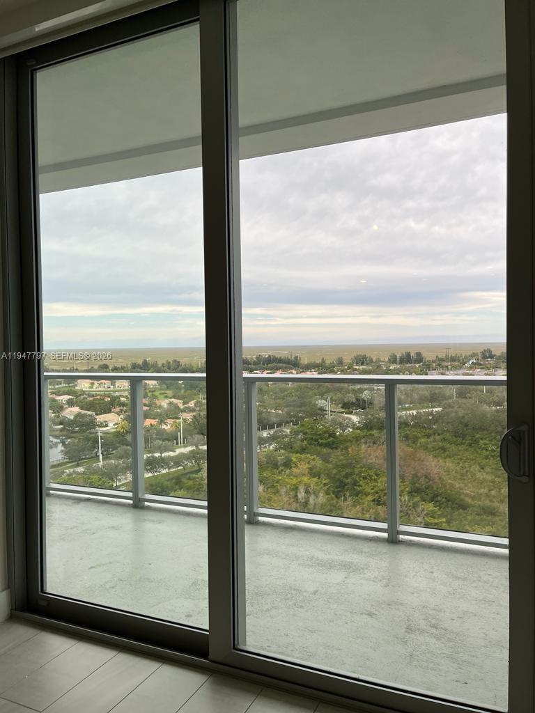 A view of a suburban landscape and horizon through a large glass sliding balcony door — 2000 Metropica Way # 1602, Sunrise FL 33323, SUNRISE, FL