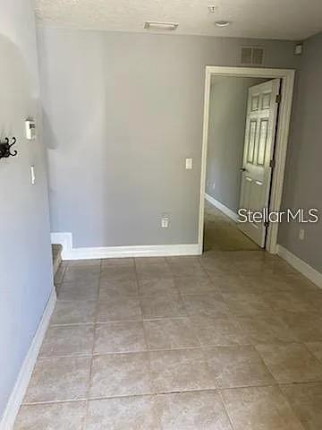 A room with light gray walls and beige tile flooring leads to an open doorway — 4511 BAY SPRING COURT, TAMPA, FL
