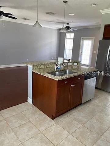 A kitchen island with a granite countertop and sink sits in a room with tile flooring — 4511 BAY SPRING COURT, TAMPA, FL