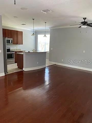 An open-concept kitchen with dark wood cabinets and a curved island overlooks a living area — 4511 BAY SPRING COURT, TAMPA, FL