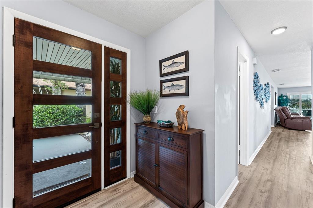 A foyer features a dark wood front door, a matching cabinet, and light wood flooring — 29 PELICAN LANE, EDGEWATER, FL