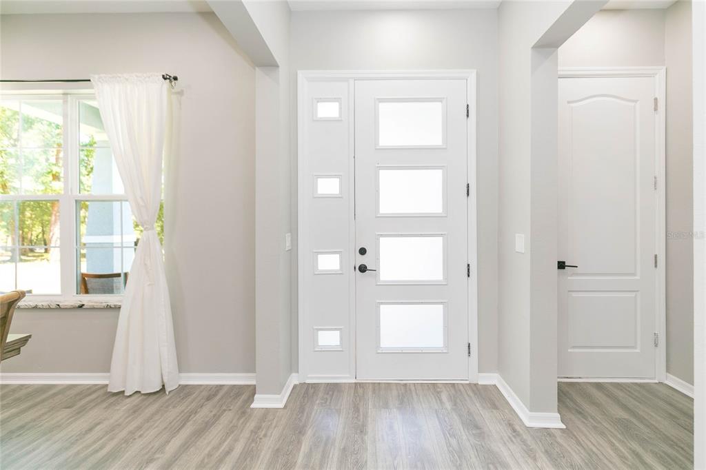 An entryway features light wood-look flooring, a white front door with glass panels, and walls — 35369 RUFFING ROAD, DADE CITY, FL