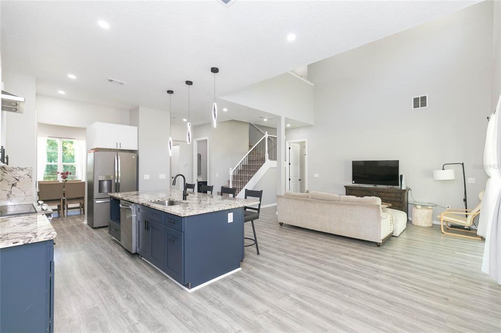 An open-concept kitchen and living area featuring a blue island, granite countertops, and light flooring — 35369 RUFFING ROAD, DADE CITY, FL