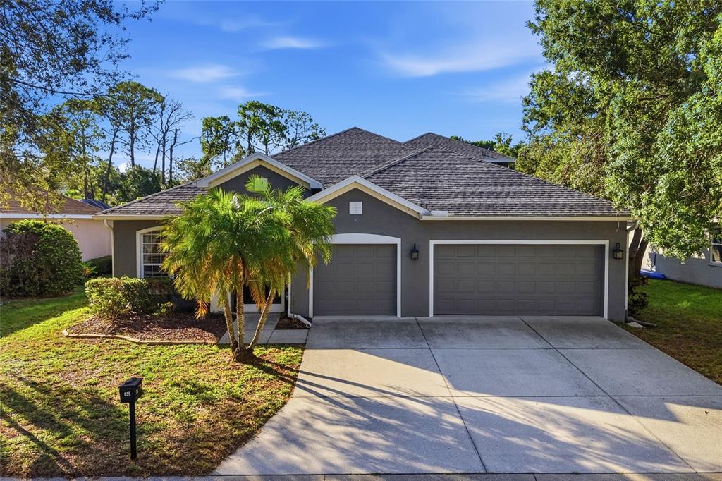 A gray single-story house with a three-car garage and a palm tree in the yard — 835 CEDARCREST COURT, SARASOTA, FL