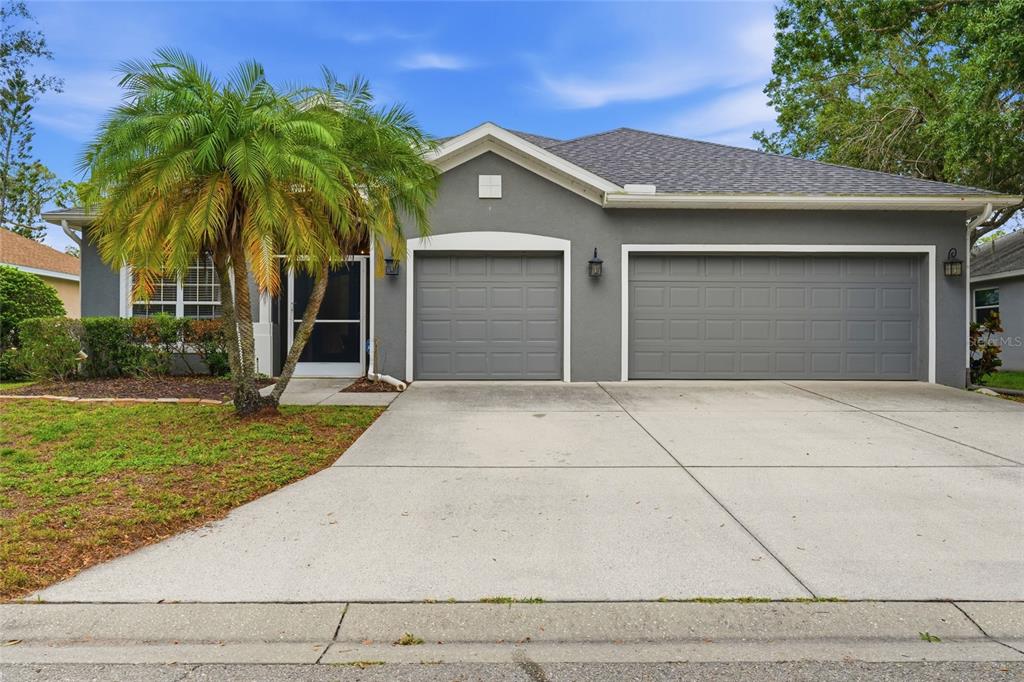 A gray single-story house with a two-car garage and a palm tree in the front — 835 CEDARCREST COURT, SARASOTA, FL