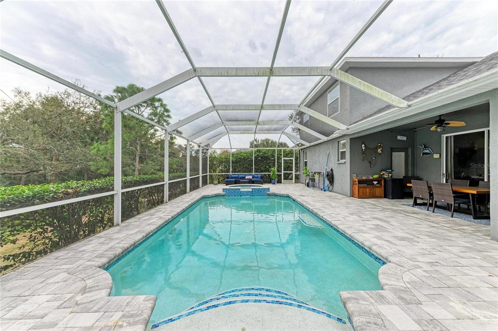 A screened-in patio features a swimming pool with a spa and a paved deck — 835 CEDARCREST COURT, SARASOTA, FL