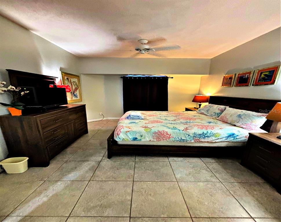 A bedroom features a king bed, dark wood furniture, tile flooring, and a ceiling fan — 300 N ATLANTIC AVENUE UNIT 1908, DAYTONA BEACH, FL