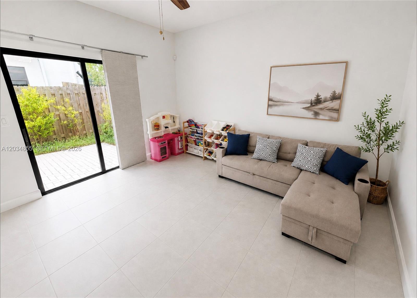 A living room features a beige sectional sofa, toy storage, and a sliding glass door — 20866 NE 7th Pl, Miami FL 33179, MIAMI, FL