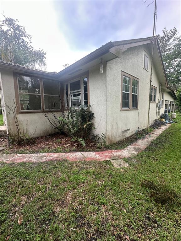 The exterior of a stucco house features a screened-in porch and a stone walkway — 237 BROAD STREET, MASARYKTOWN, FL