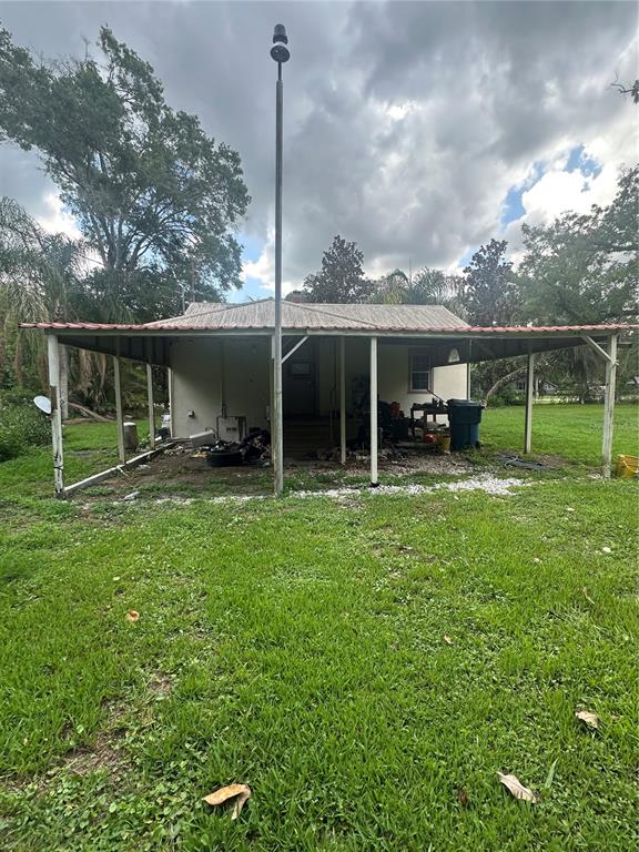A single-story house features a wide, covered porch supported by wooden posts under a metal roof — 237 BROAD STREET, MASARYKTOWN, FL