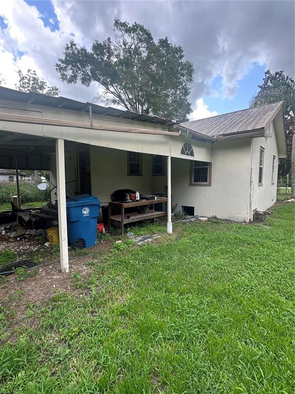 A side view of a house with a covered patio, a blue bin, and yard — 237 BROAD STREET, MASARYKTOWN, FL