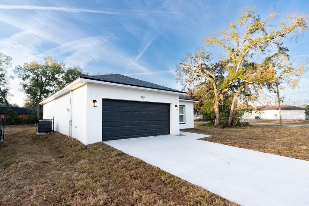 A white detached garage with a black door and a concrete driveway sits on grass — 50 W 12TH STREET, APOPKA, FL