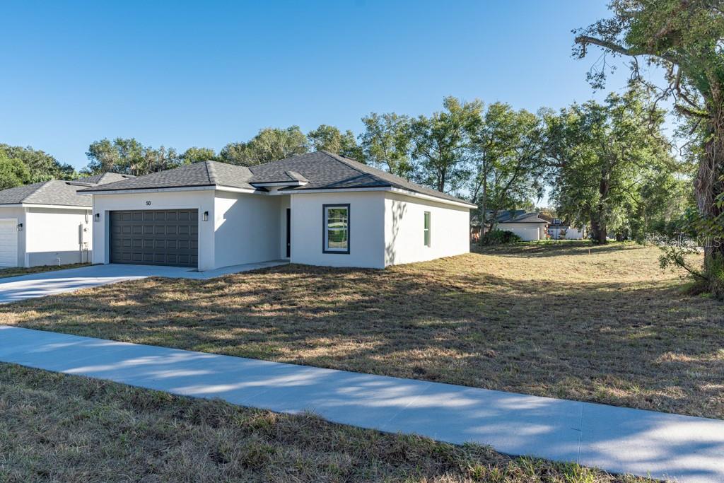 A newly constructed single-story house with a white exterior, dark roof, and a two-car garage — 50 W 12TH STREET, APOPKA, FL