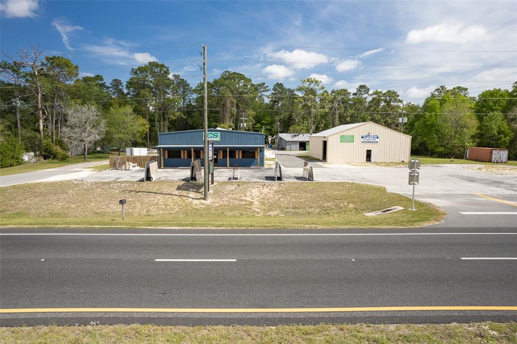 An exterior view of two commercial buildings with a parking lot and surrounding trees — 14131 NE HIGHWAY 27 ALT, WILLISTON, FL