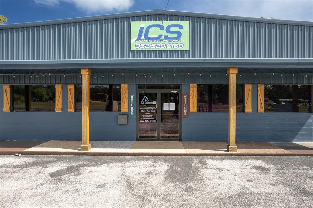 The exterior of a blue metal building features a sign for ICS Cabinets & Stoneworks — 14131 NE HIGHWAY 27 ALT, WILLISTON, FL