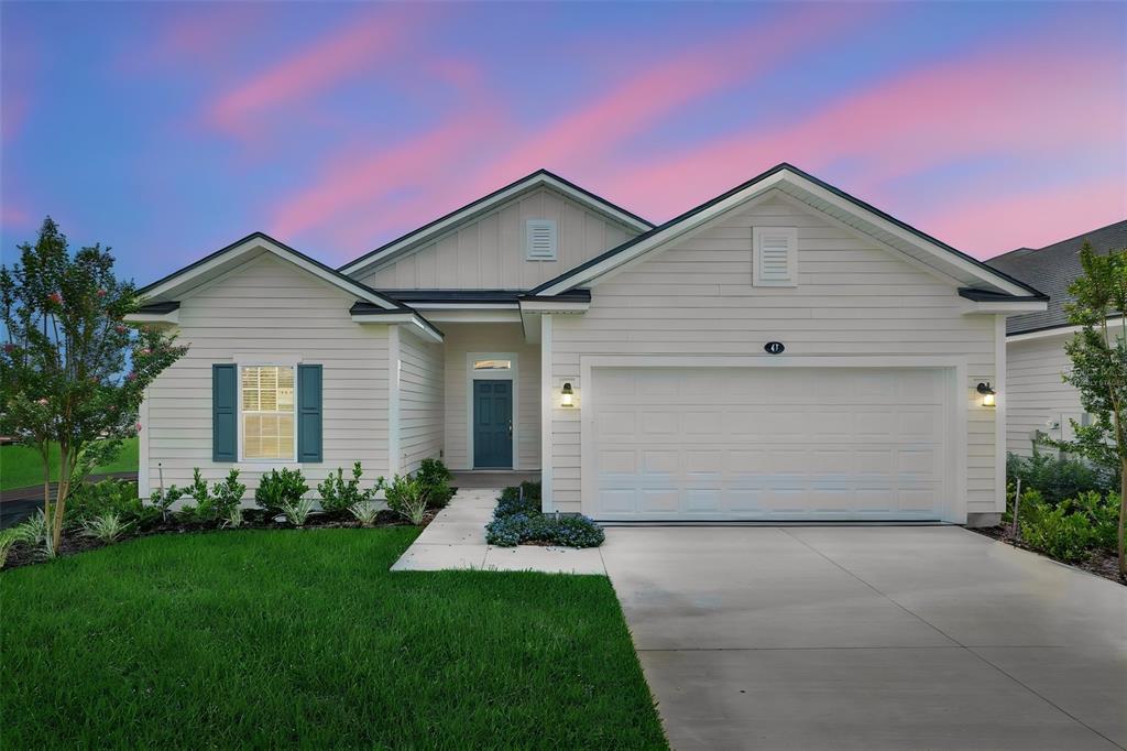 A single-story house with light siding, a two-car garage, and a dark blue front door — 47 WINDMILL PALM WAY, PALM COAST, FL