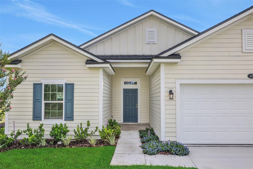 A single-story house with cream horizontal siding, blue shutters, and a dark blue front door — 47 WINDMILL PALM WAY, PALM COAST, FL