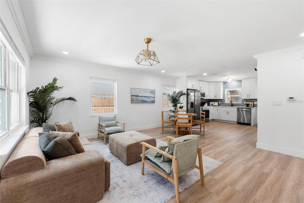An open-concept living and dining area features light wood flooring and white kitchen cabinetry — 4733 25TH AVENUE S, ST PETERSBURG, FL