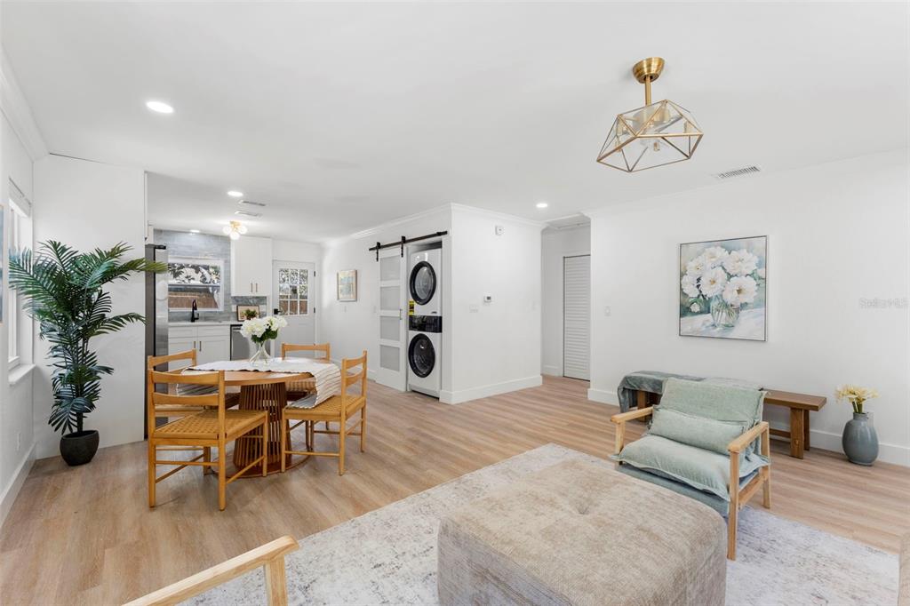 A bright living and dining area features light wood flooring, white walls, and laundry appliances — 4733 25TH AVENUE S, ST PETERSBURG, FL