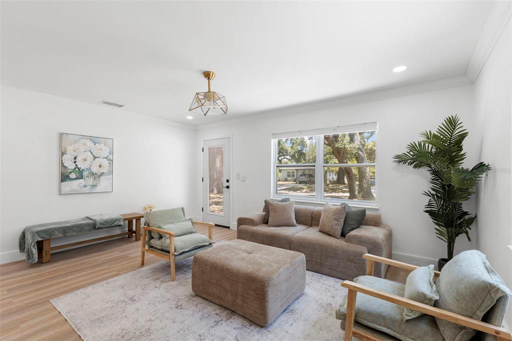 A living room features light wood floors, a neutral sofa, two armchairs, and a bench — 4733 25TH AVENUE S, ST PETERSBURG, FL