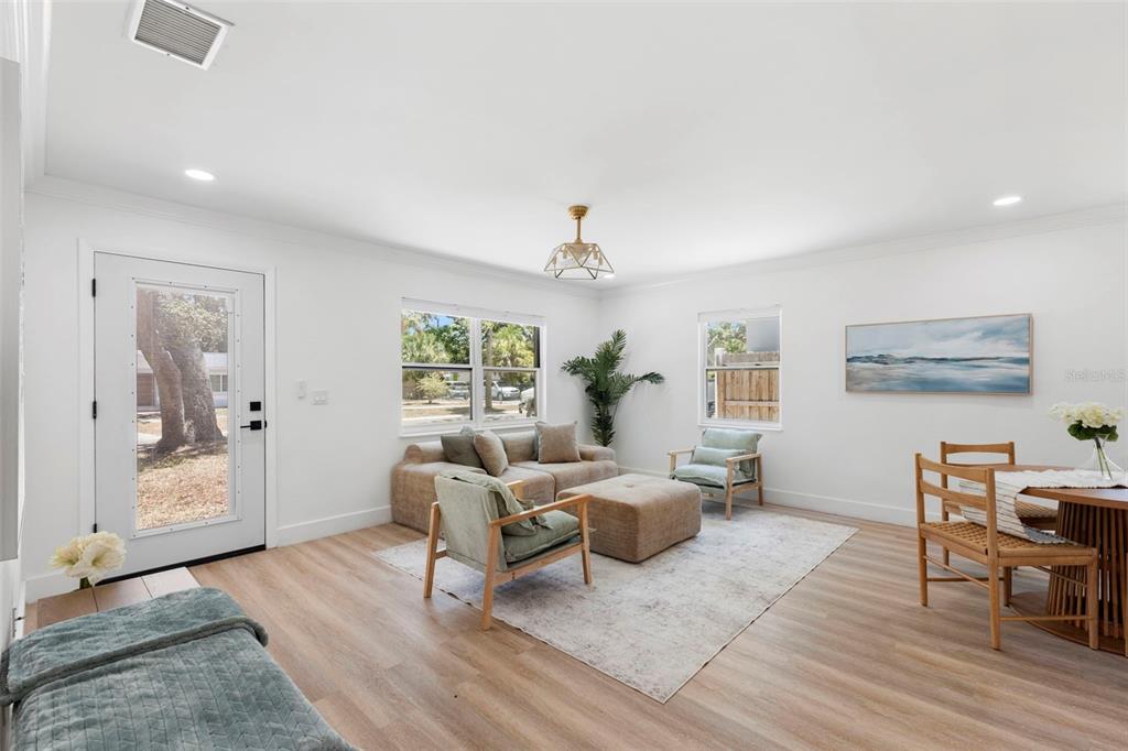 A bright living room features light wood flooring, a sectional sofa, and a dining area — 4733 25TH AVENUE S, ST PETERSBURG, FL