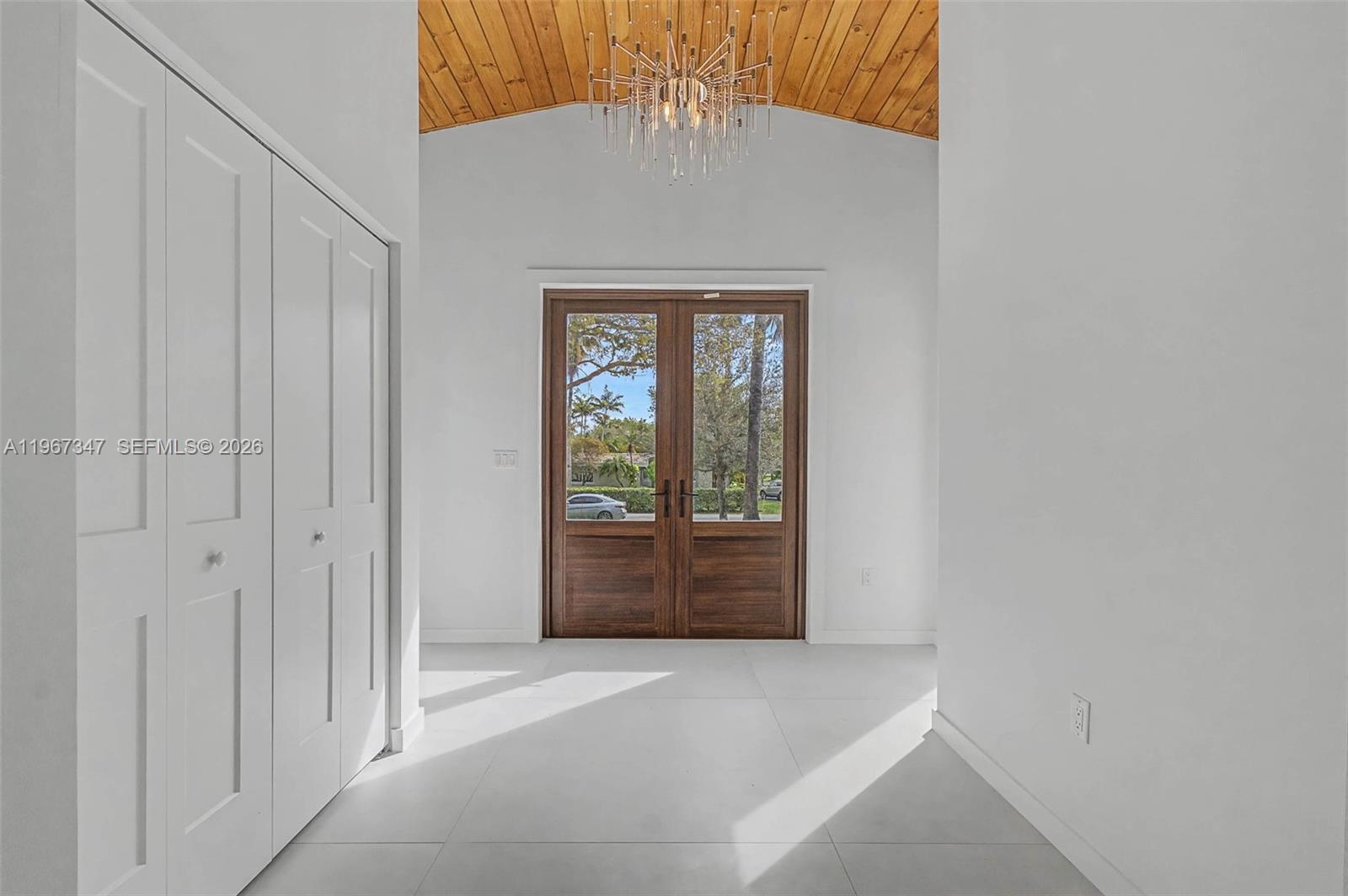 An entryway features white tile floors, a wood-paneled vaulted ceiling, and double glass front doors — 12940 SW 73rd Ave, Pinecrest FL 33156, PINECREST, FL