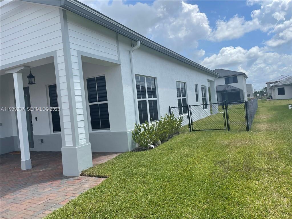 A white house exterior features a covered patio, a chain-link fence, and a grassy yard — 4919 Frattinas # 4919, Ave Maria FL 34142, AVE MARIA, FL