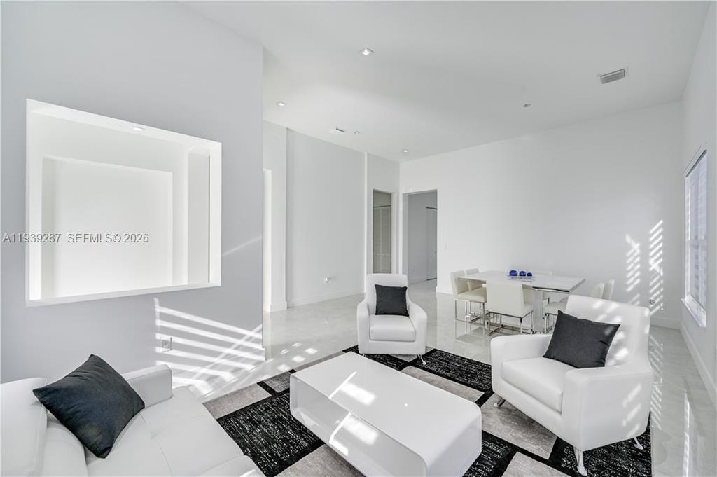 A modern living and dining area features white furniture, tiled floors, and a recessed wall niche — 4919 Frattinas # 4919, Ave Maria FL 34142, AVE MARIA, FL
