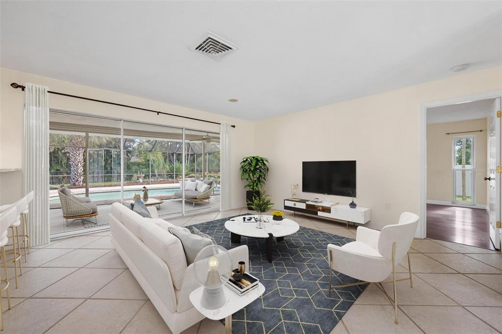 A bright living room features a white sofa, patterned rug, and sliding doors overlooking a pool — 1011 PINE FOREST COURT, VENICE, FL