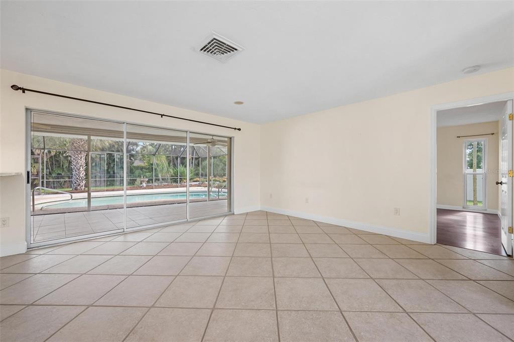 A bright room with beige tile flooring, sliding glass doors, and a view of a pool — 1011 PINE FOREST COURT, VENICE, FL