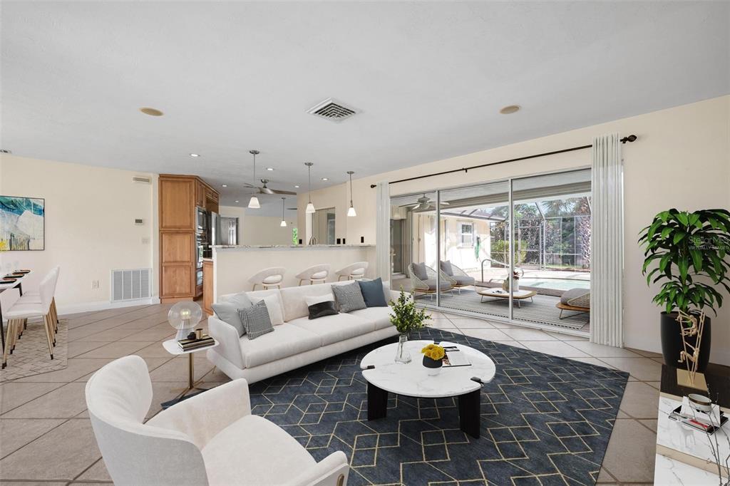 A living room with tile floors, a white sofa, and a sliding glass door to a pool — 1011 PINE FOREST COURT, VENICE, FL