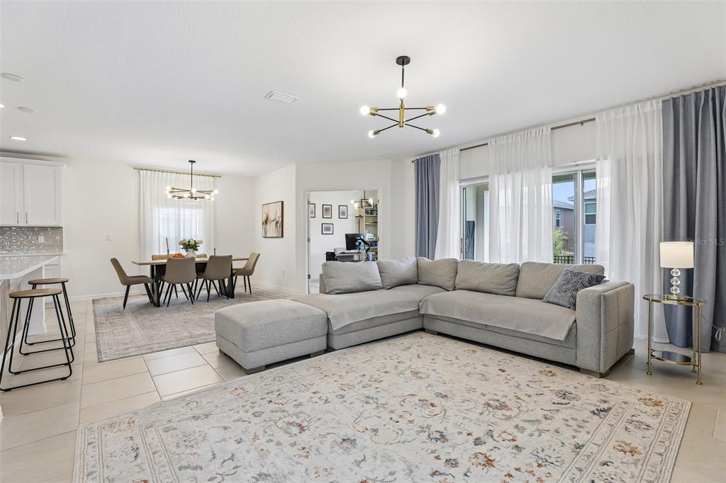 An open-concept living and dining area features a gray sectional sofa and modern light fixtures — 1581 SWAN SWIM DRIVE, DAVENPORT, FL