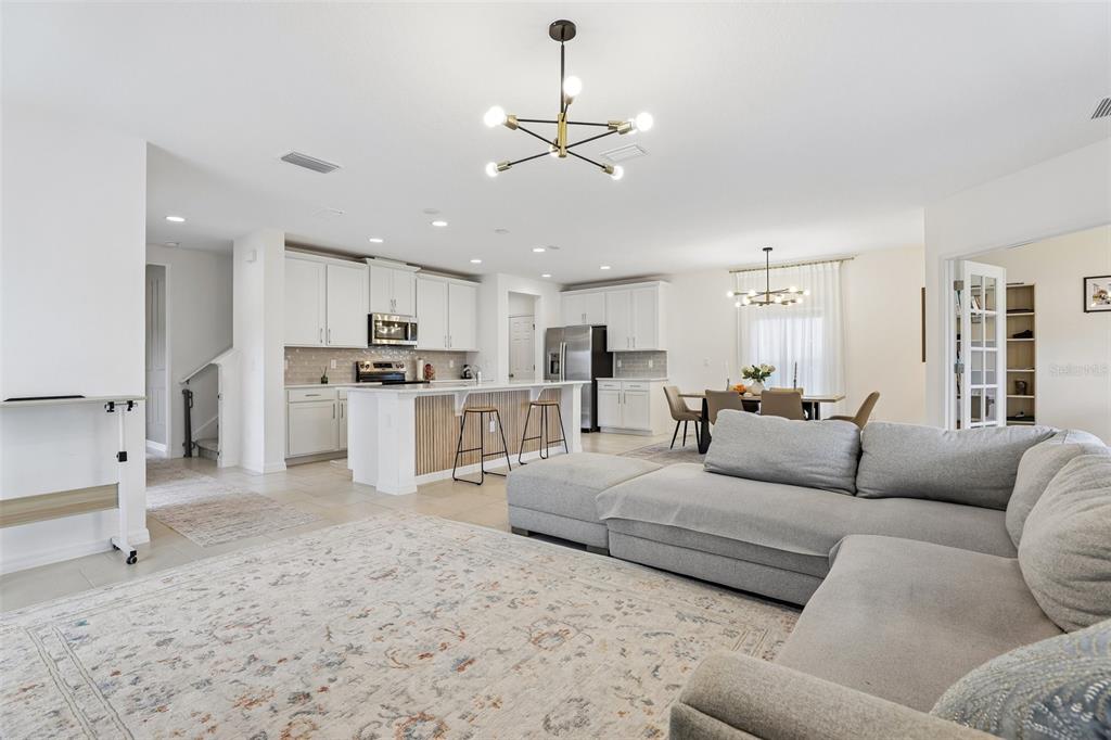An open-concept living room and kitchen featuring white cabinetry, a large island, and neutral furniture — 1581 SWAN SWIM DRIVE, DAVENPORT, FL