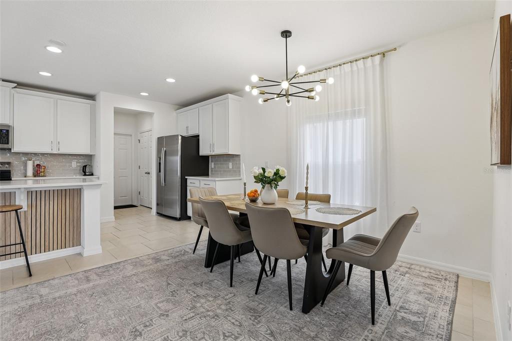 A dining area features a modern chandelier, a wooden table with chairs, and a rug — 1581 SWAN SWIM DRIVE, DAVENPORT, FL