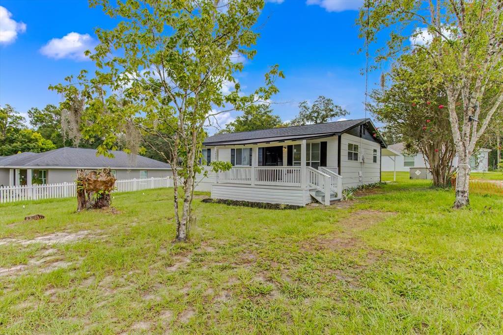 A white house with a front porch sits on a grassy lot with trees — 1450 3RD STREET, ORANGE CITY, FL