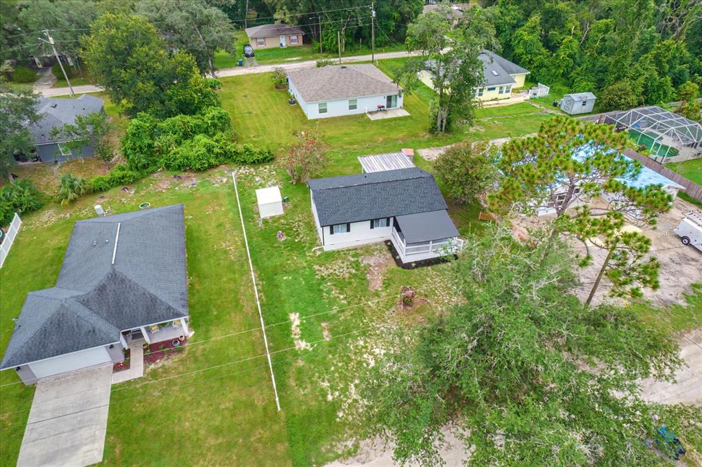 An aerial view shows two houses with dark roofs, a pool enclosure, and surrounding grassy yards — 1450 3RD STREET, ORANGE CITY, FL