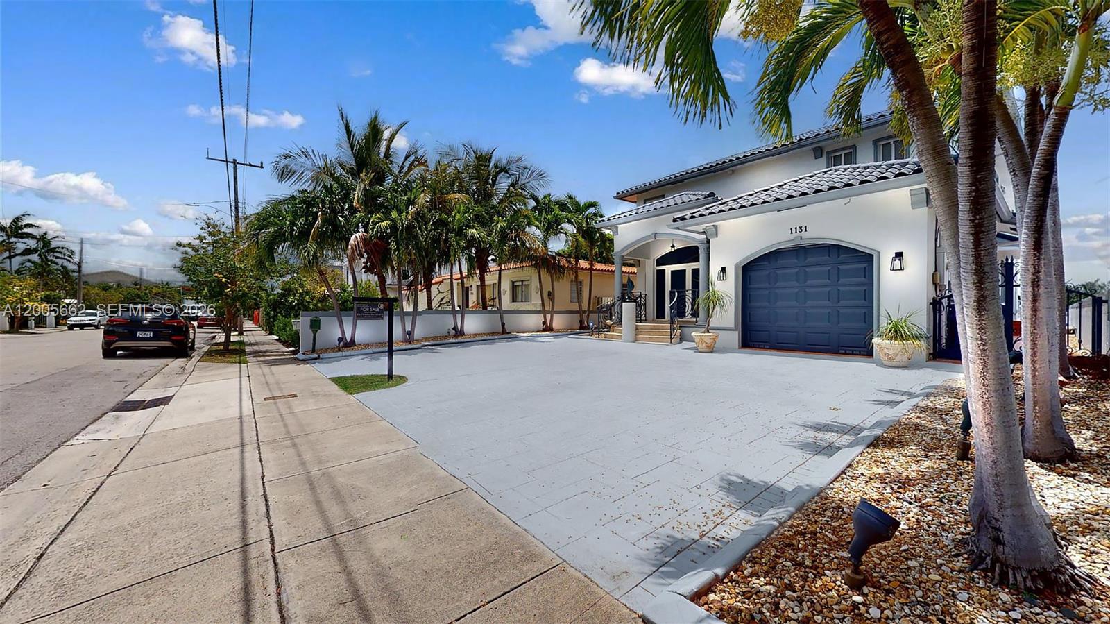 A two-story house with a blue garage door, a paved driveway, and palm trees — 1131 Stillwater Dr, Miami Beach FL 33141, MIAMI BEACH, FL
