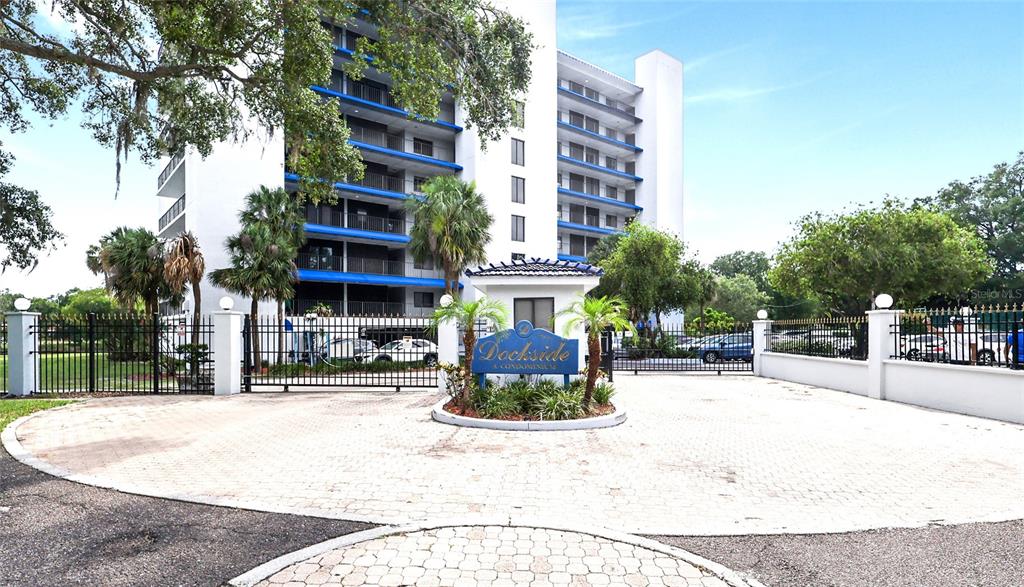 A multi-story white condominium building stands behind a gated entrance with a circular driveway — 2780 N RIVERSIDE DRIVE UNIT 502, TAMPA, FL