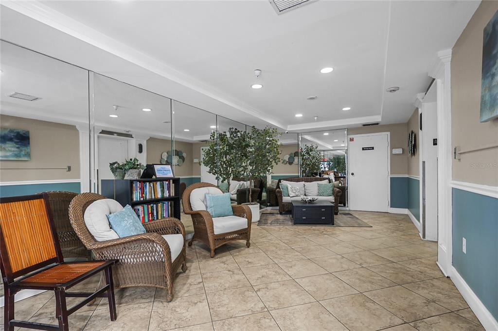 A lobby area features wicker chairs, a small bookshelf, mirrored walls, and tiled flooring — 2780 N RIVERSIDE DRIVE UNIT 502, TAMPA, FL